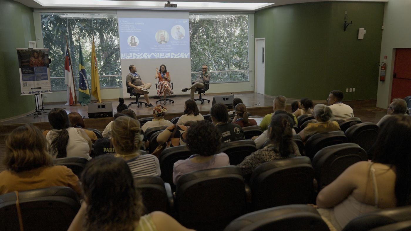 Plateia acompanha um painel do II Fórum Socioeconômico Ambiental Amazônia Viva, com três participantes no palco e a programação projetada ao fundo.
